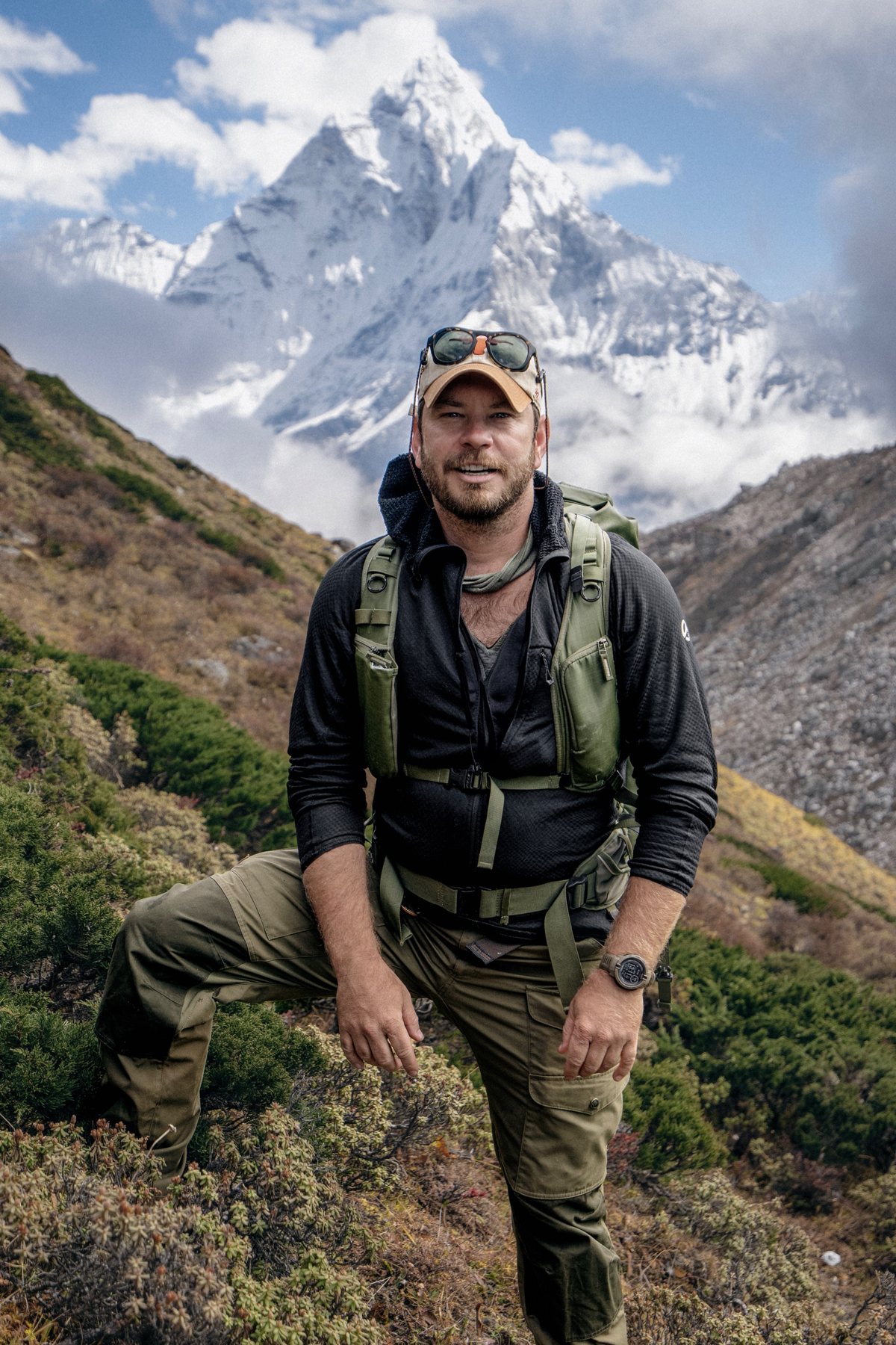 Caleb Bonham on a Himalayan trail with a snow-capped peak behind him